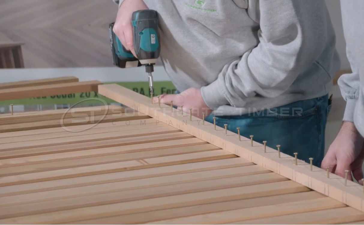 Installer using stainless steel screws to fix timber battens correctly, demonstrating proper fixings for cladding and fencing to prevent black staining.